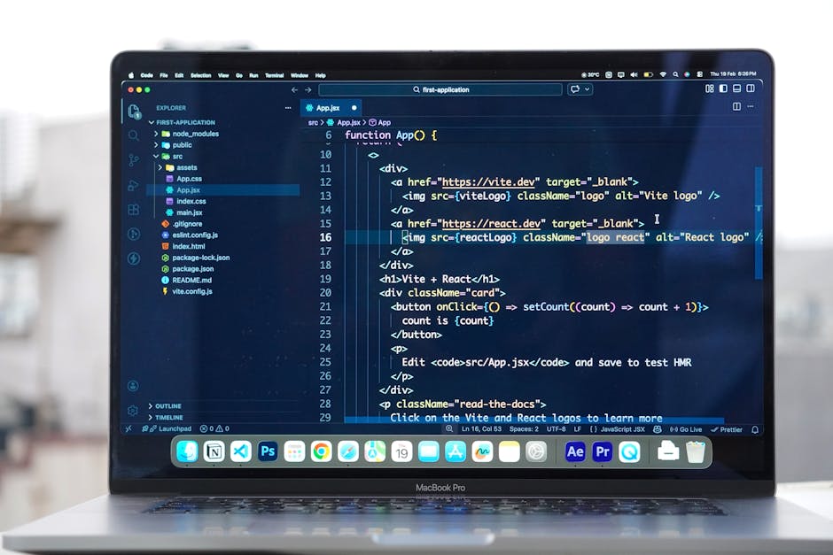 The image shows a MacBook Pro laptop with a modern, slim design, placed on a surface near a window overlooking an urban landscape with multiple buildings in the background. The screen displays a dark-